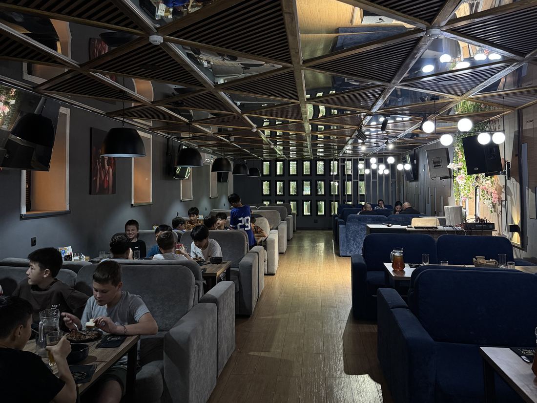Диваны мен айналы төбесі бар Podium Bar-дың кең залы